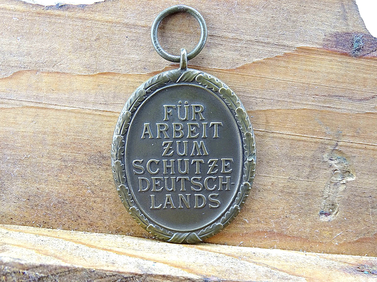 Schutzwall Ehrenzeichen, Buntmetall mit neuwertigem Originalband, ca.20 cm Bandabschnitt